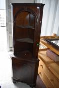 A reproduction mahogany effect corner shelf having cupboard under