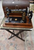 A traditional folding card table and a hand crank sewing machine, American, labelled Wheeler and