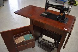 An early 20th Century Singer treadle sewing machine in cabinet, with some accesories