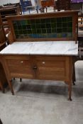 An Arts and Crafts style golden oak washstand, having marble top and tiled back, width approx. 122cm