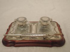 A modern silver pen and ink stand having a pair of glass bottles with decorative silver lids with
