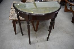 A reproduction demi lune hall table having leather inset under glass, width approx. 74cm, on