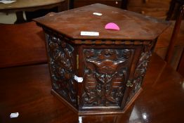 An interesting and unusual corner cupboard of small proportions having carved figure heads to all