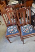A set of four early 20t Century mahogany dining chairs having rail backs and woolwork drop in seats