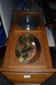 A wood framed wall clock with pendulum