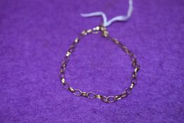 A yellow metal bracelet having hoop form links stamped 9kt