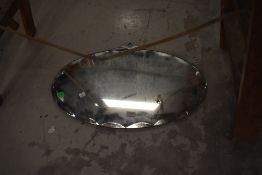 A vintage frameless oval wall mirror