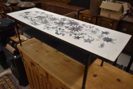 A vintage coffee table, similar to Piper, ply and laminate top having foliate decoration, metal