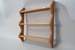 A natural pine triple wall shelf of small proportions with plate grooves to each and shaped ends,