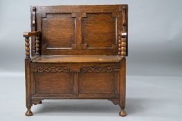 An early to mid 20th Century oak monks bench having plain top, panelled back and box section, bobbin