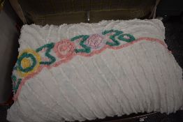 A suitcase containing a vintage candlewick bed throw, an ochre nylon double bed throw in packaging