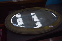 A late 19th or early 20th Century brass framed oval wall mirror, in an Arts and Crafts style,