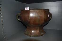 A hexagonal bronze form planter having twin dragon head handles, base plate loose