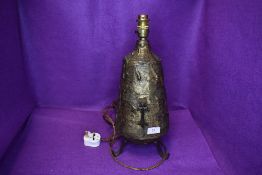 A arts and crafts style table lamp base with metal work body and crucifix decoration on three footed