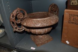 A cast iron urn or planter having ornate scroll handles