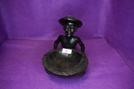 An ethnic wood carved figure of a tribal man holding a dish