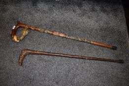 Two walking sticks one naturalistic and one with handle carved as eagle eating cobra