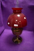 An Aladdin oil burning lamp having red glass shade