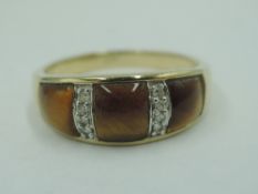 A 9ct gold band ring having three tiger's eye panels interspersed by two rows of diamond chips, size