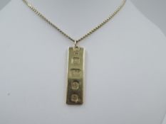 A 9ct gold ingot pendant having oversized London 1978 hallmarks on a yellow metal chain stamped