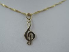 A yellow metal pendant in the form of a musical treble clef, stamped 585 on a 9ct gold fine rope