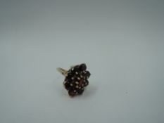 An oval garnet triple cluster dress ring having a raised basket mount on a 9ct gold loop, size O &