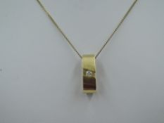 A yellow metal Artisan pendant having a tension set diamond solitaire, no marks, tested as 18ct gold