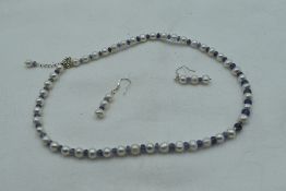 A string of cultured pearls with rough cut tanzanite spacers and matching drop earrings all having