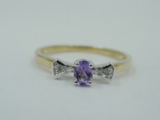An amethyst dress ring flanked by two diamond chips in raised mounts on a 9ct gold loop, size M &