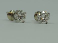 A pair of diamond solitaire stud earrings, total approx 1ct in white metal four claw mounts with