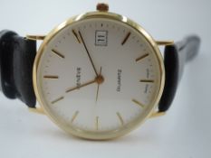 A 9ct gold Geneve quartz wrist watch having a baton numeral dial with date aperture to white face in