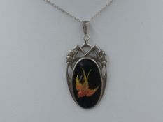 A silver and enamel pendant by Charles Horner having an iridescent yellow and orange swallow on