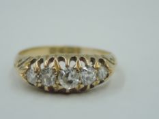 A graduated five stone diamond ring in a claw set gallery mount to engraved shoulders on an 18ct