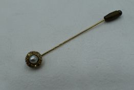 A yellow metal stick pin having a split pearl and diamond chip cluster, approx 2.9g