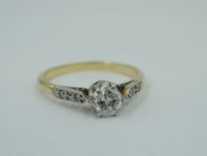A diamond solitaire, approx 0.25ct dress ring in a raised claw set mount to diamond chip set