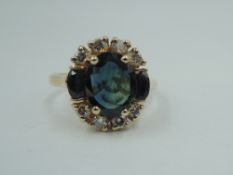 A sapphire and diamond ring having a central blue-green oval sapphire, approx 1ct flanked by two