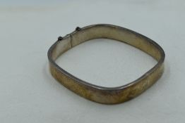 A silver hinged bangle of plain canted square form, missing safety chain, approx 15g