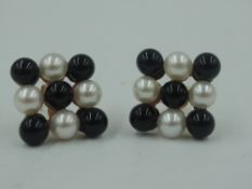A pair of black and white cultured pearl stud earrings in a chequered pattern in yellow metal mounts