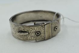 A 1950's silver hinged belt bangle having engraved scroll decoration, approx 25.1g, (missing