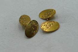A pair of 9ct gold oval panel cufflinks having engraved scroll decoration and chain connectors,
