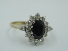 A sapphire and cubic zirconia cluster dress ring having diamond set shoulders on a 9ct gold loop,