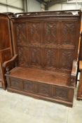 A 19th Century oak box settle having carved high back with double rail over, scroll arms with turned