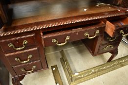 An early 20th Century mahogany desk or dressing table having skiver leather top, gadrooned edge on