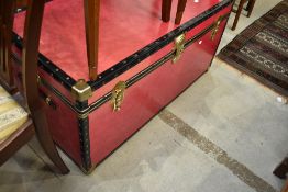 A large travel trunk having brass clasp and corners, currently locked but appears to be empty