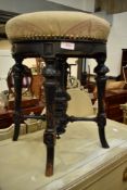 A Victorian ebonised piano stool having later upholstered seat