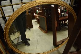 A late 19th or early 20th Century gilt plaster oval wall mirror, approx 110 x 140cm, current fixings