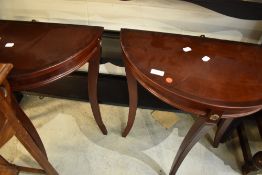 A pair of reproduction mahogany effect demi lune hall tables