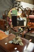 An early 20th Century ornate brass toilet mirror