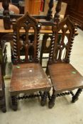 A pair of Victorian Gothic oak hall chairs having twist frames