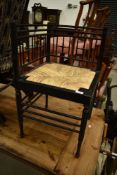 A Victorian Aesthetic style ebonised corner chair having refurbished rush seat